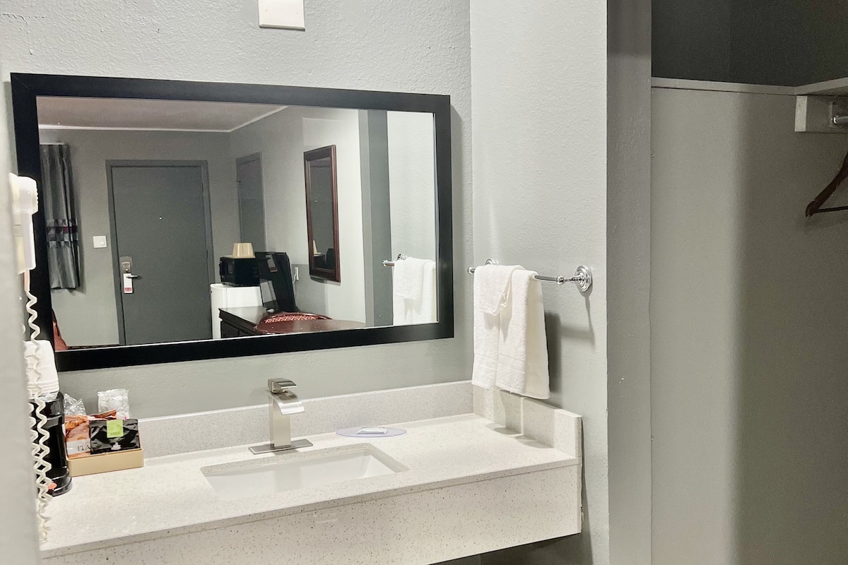 A bathroom with a large mirror, a sink, and a towel rack.