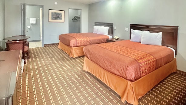 Habitación de hotel con dos camas, un escritorio y zona de ducha.