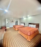 Habitación de hotel con dos camas, un escritorio y zona de ducha.