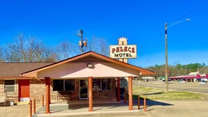 Un motel con un letrero llamativo, una entrada techada y un amplio estacionamiento.