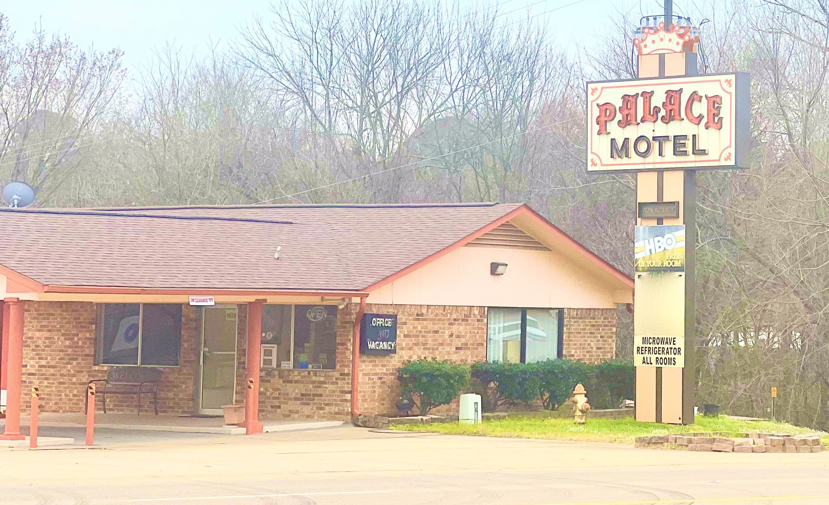 Ein Motel mit einem Schild, das "Palace Motel" zeigt, ein Backsteinhaus und ein Schild mit der Aufschrift "Personal gesucht".