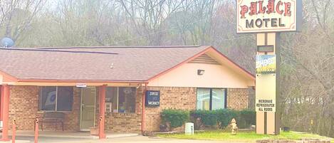 A motel with a sign reading "Palace Motel," a brick building, and a sign indicating "Office Vacancies."