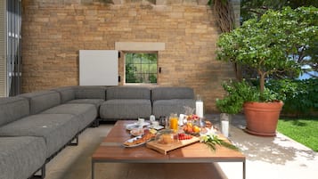 Relax in style with a comfortable sofa and enjoy a delicious breakfast in this inviting outdoor seating area.