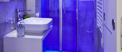 A modern bathroom with a glass shower enclosure, a white sink, and a toilet.