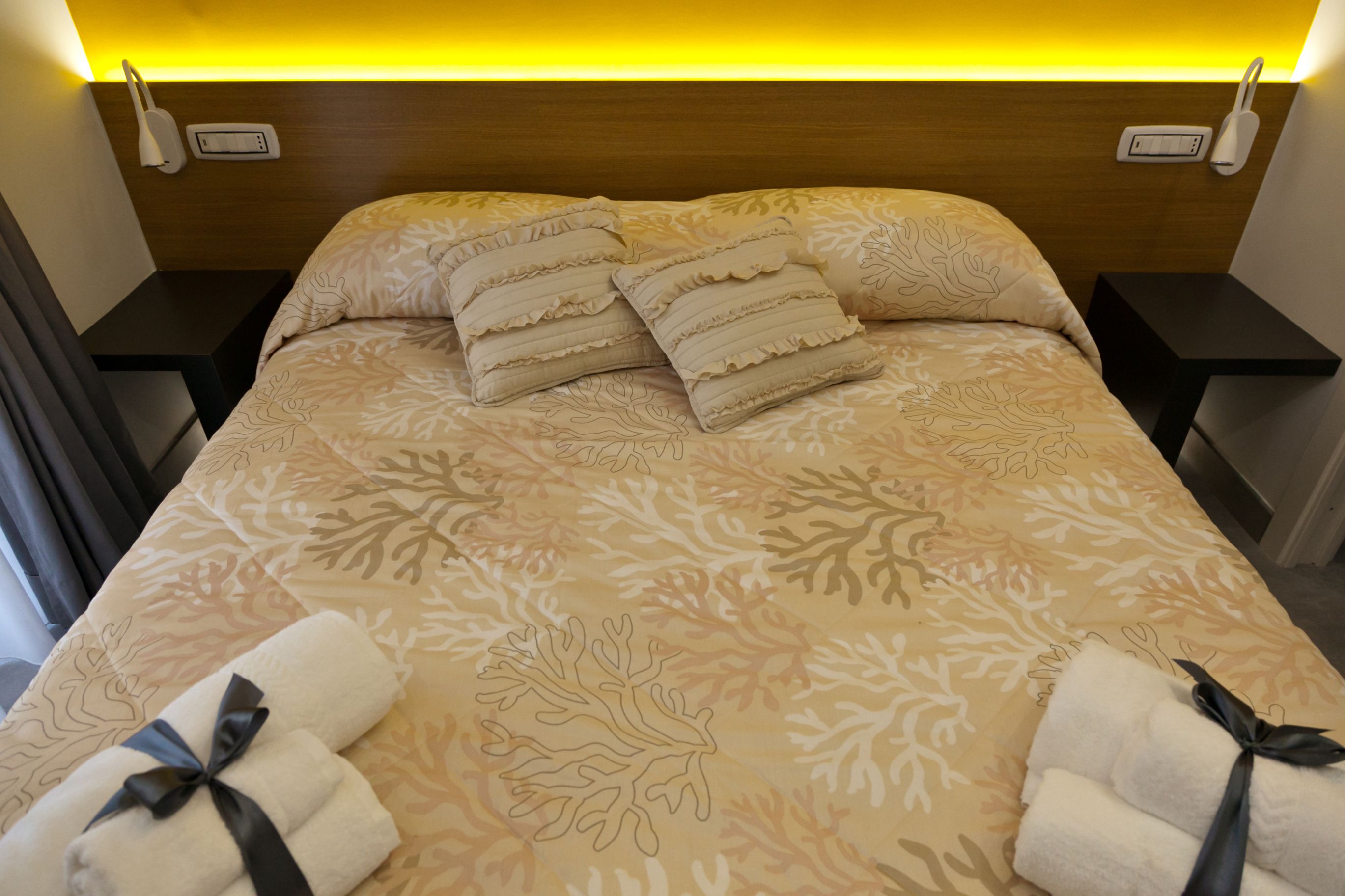 A neatly made bed with patterned bedding and two bedside tables, each with a power outlet.