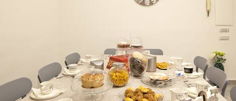 A dining table set for a meal with various dishes, a clock, and a vase with flowers.