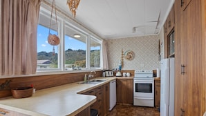 Una cocina con armarios de madera, una estufa blanca y un fregadero.