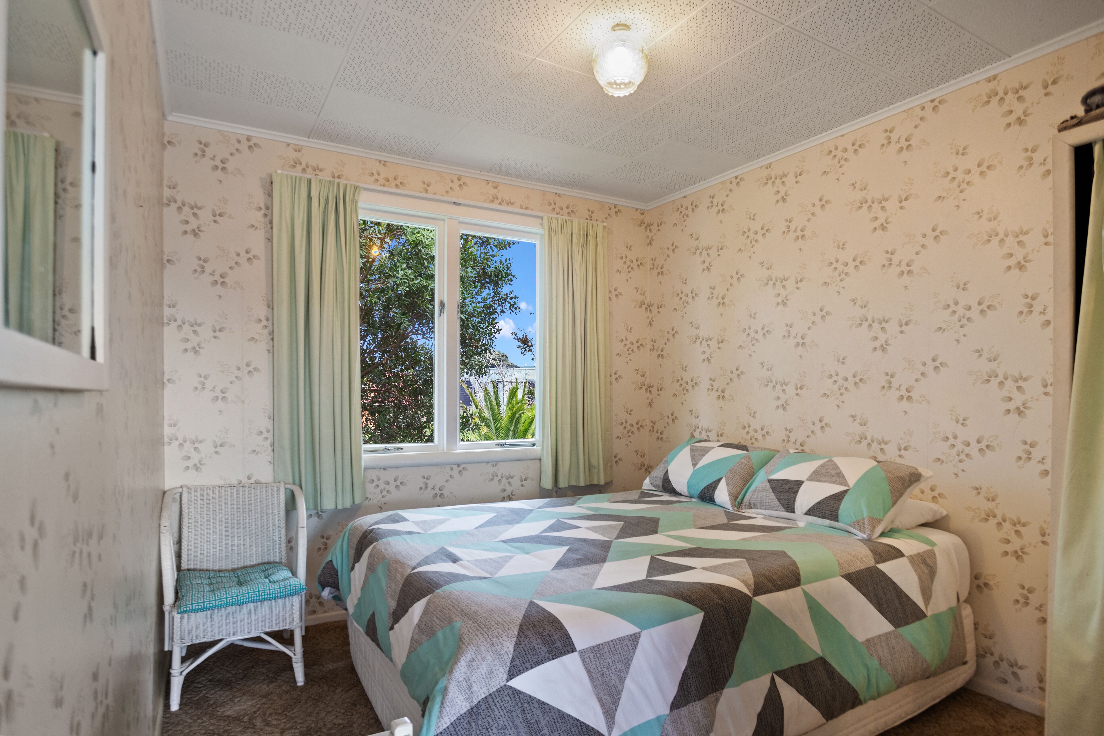A bedroom with a bed, a chair, and a window.
