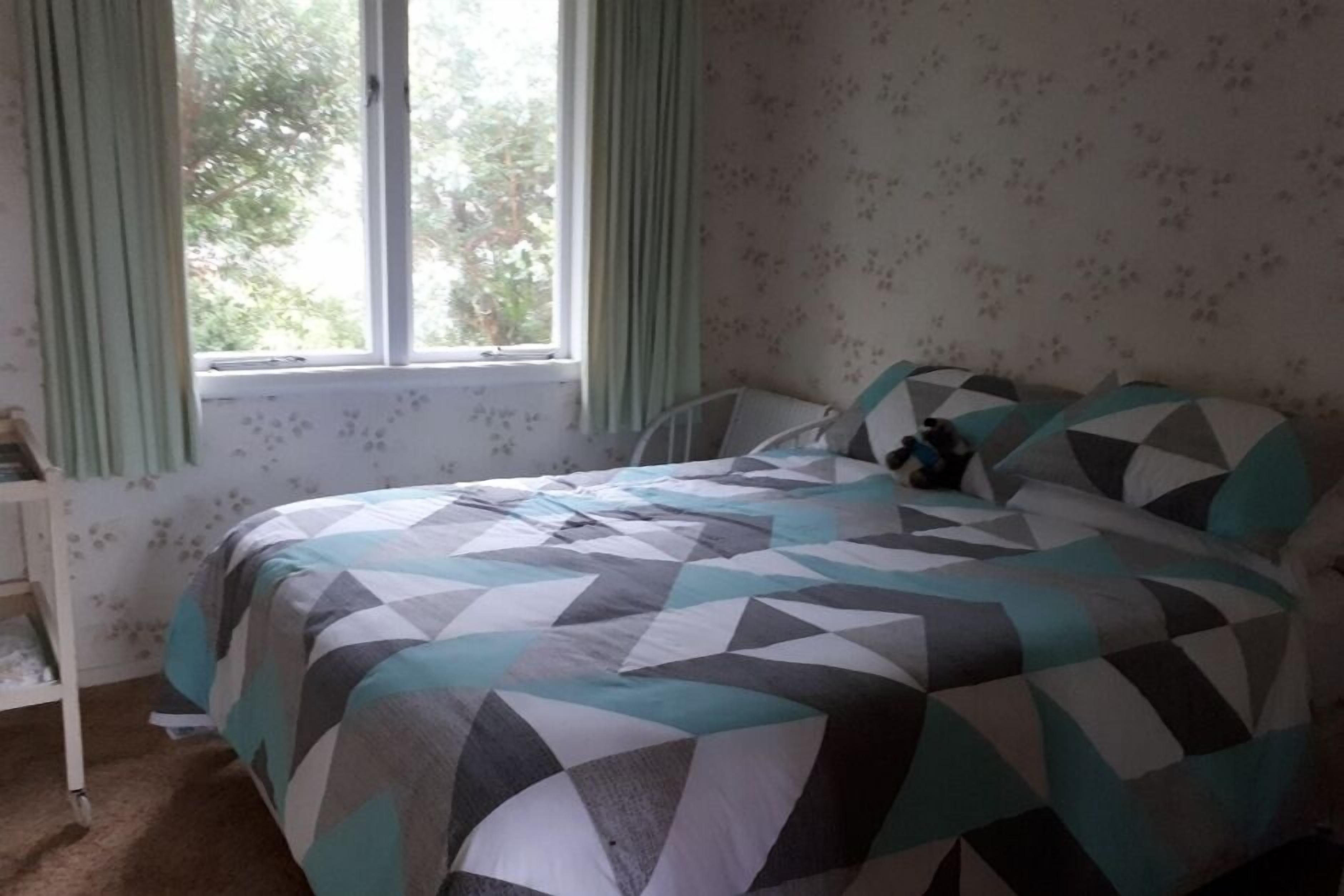 A bedroom with a bed, curtains, and a window.