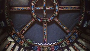 Una finestra de vitralls circulars amb una creu al centre, envoltada d'ornaments complexos.