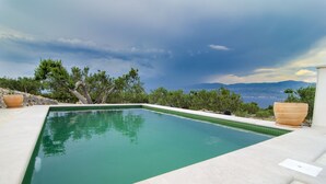 Une piscine rectangulaire à l’eau d’un bleu limpide, entourée d’une terrasse carrelée aux couleurs claires.