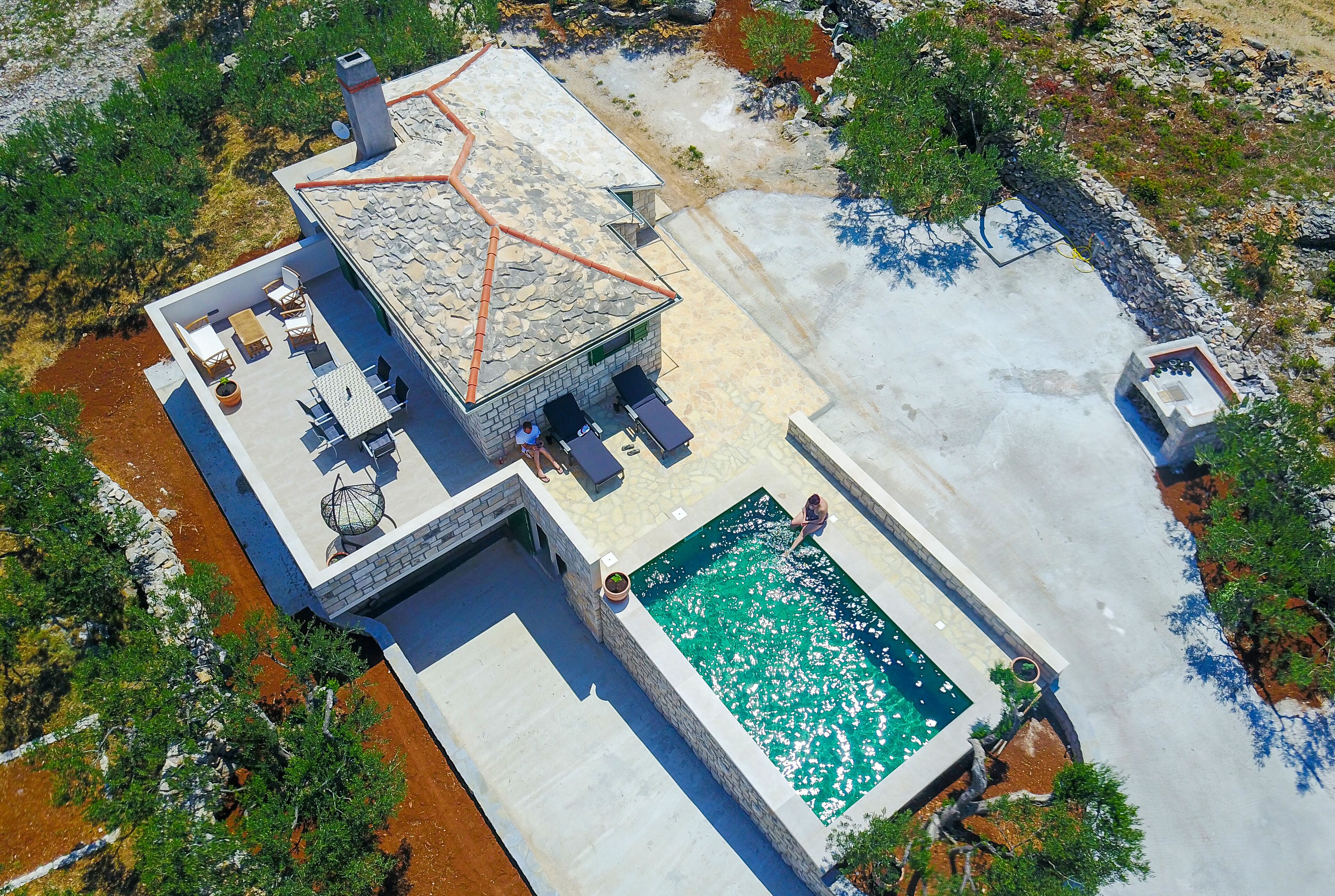 A modern house with a stone roof, a swimming pool, and outdoor furniture.