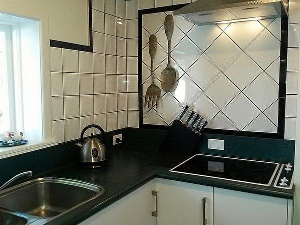 A modern kitchen with a stainless steel kettle, a sink, and a black countertop.