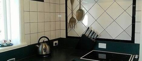 A modern kitchen with a stainless steel kettle, a sink, and a black countertop.