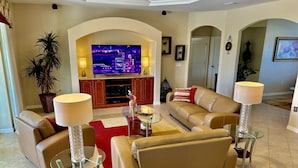 Un salon moderne avec un grand téléviseur à écran plat, des canapés en cuir, une table basse en verre et un tapis rouge.