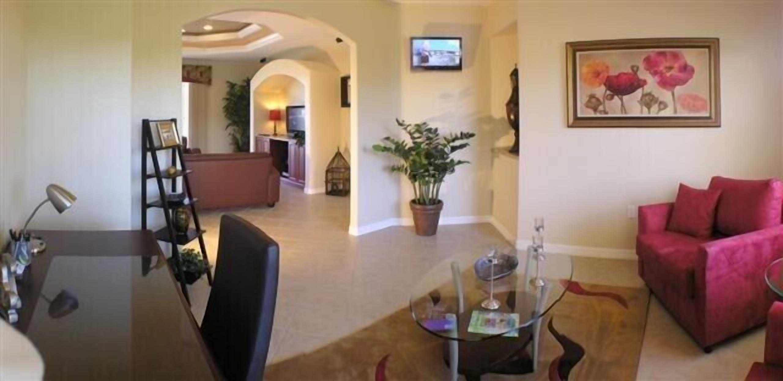 Una sala de estar con una mesa de centro de vidrio, un sofá rojo y un televisor montado en la pared.