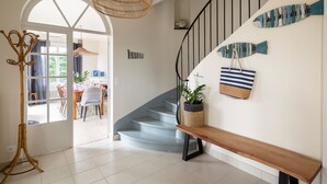 A staircase with a wooden handrail, a woven light fixture, and decorative fish wall art. - Le Sémaphore - Maison avec sauna Vue mer (Cancale)