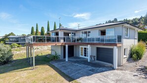 Une maison moderne à deux étages, dotée d’un balcon, d’un garage et d’une pelouse bien entretenue.