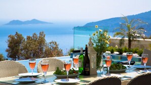 Ein Tisch ist für eine Mahlzeit gedeckt, mit Blick auf Meer und Berge.