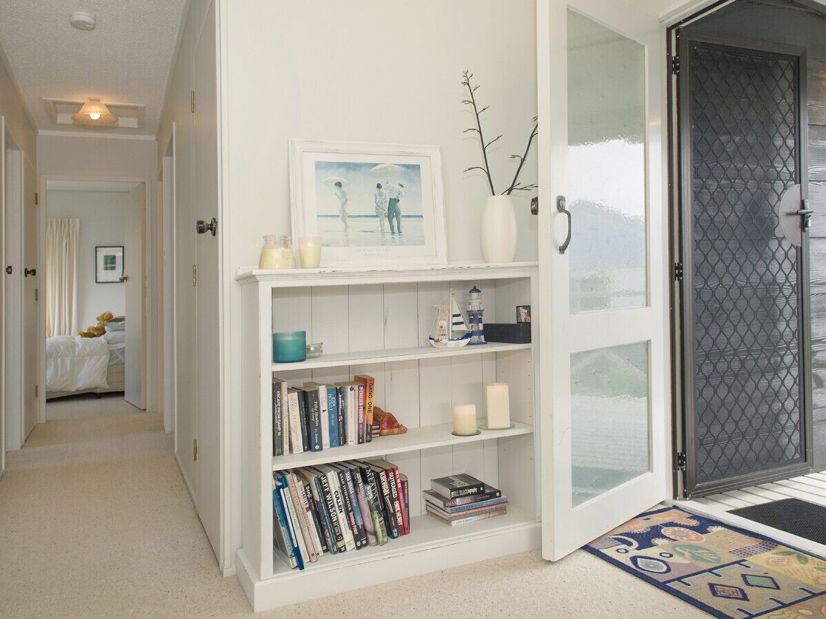 Un couloir avec une bibliothèque, un tableau encadré et une porte donnant sur un balcon.