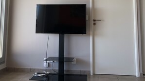 A room with a flat-screen TV mounted on the wall, a door, and a window. - Apartment bayonne T2 (Bayonne)