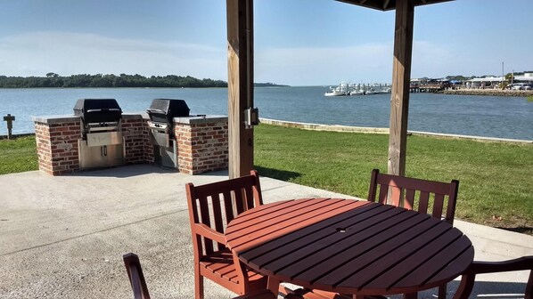 Enjoy al fresco dining with a view of the water from this patio, featuring a barbecue station and comfortable seating.