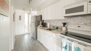 Une cuisine moderne avec des armoires blanches, des appareils en acier inoxydable et un comptoir en granit.