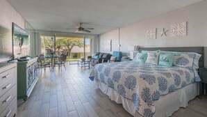 Une chambre dotée d’un grand lit, d’un coin repas avec des chaises, d’un ventilateur de plafond et offrant une vue sur l’extérieur.