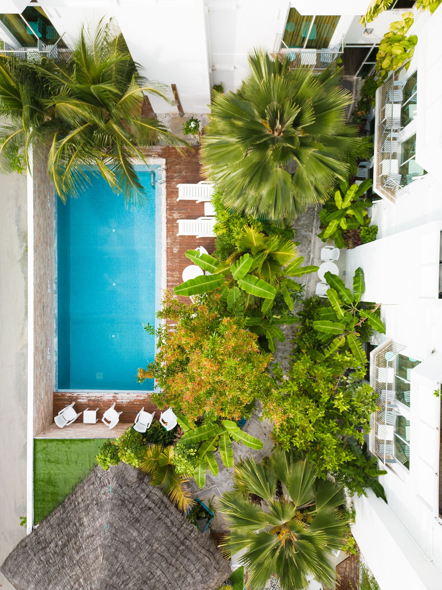 An aerial view of a hotel with a swimming pool surrounded by lush greenery and white buildings.