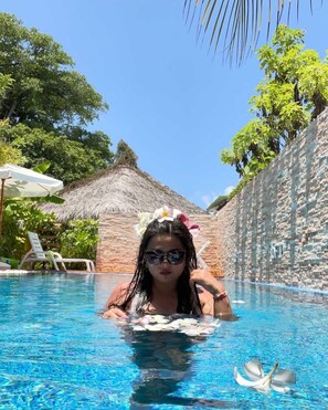 Una piscina al aire libre, sombrillas, sillones reclinables de piscina