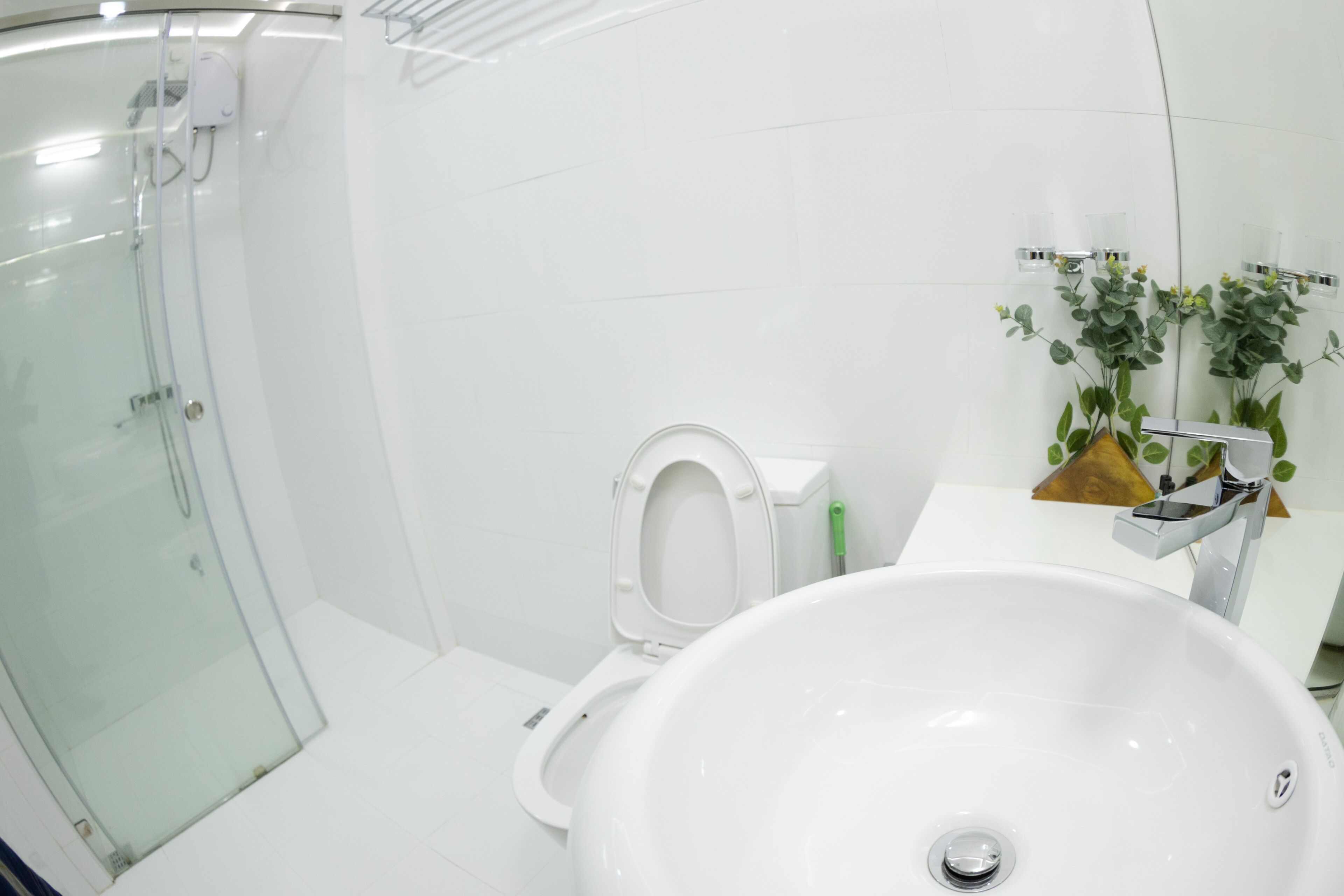 Un baño moderno con cabina de ducha de vidrio, inodoro blanco y un lavamanos grande y blanco.