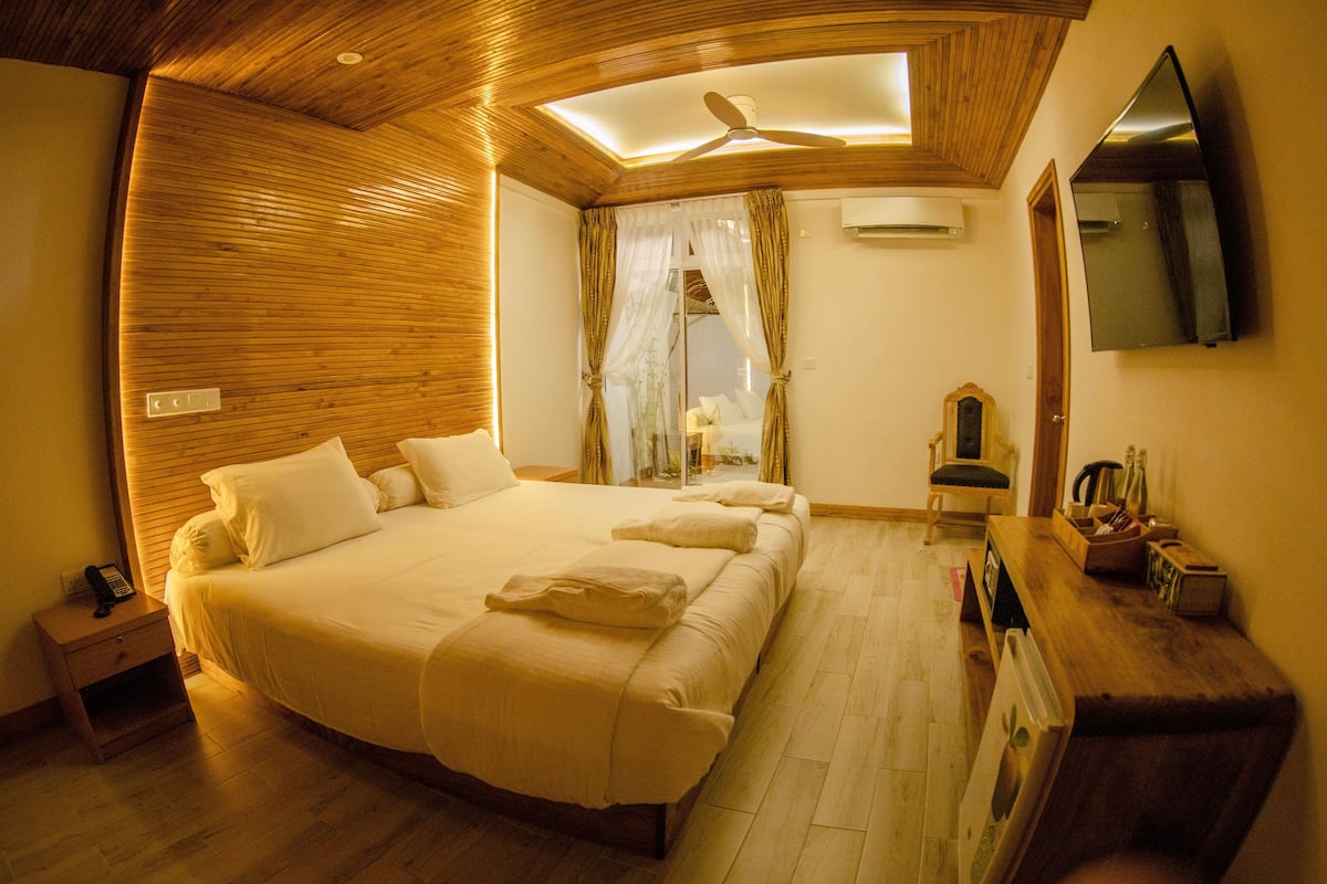 Une chambre avec un grand lit, un plafond en bois et un ventilateur de plafond.