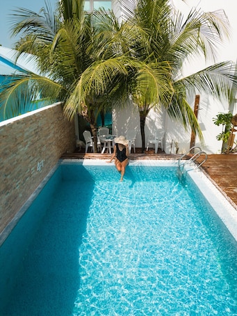 Una piscina al aire libre, sombrillas, sillones reclinables de piscina. Perla Dhangethi