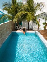 Una piscina al aire libre, sombrillas, sillones reclinables de piscina