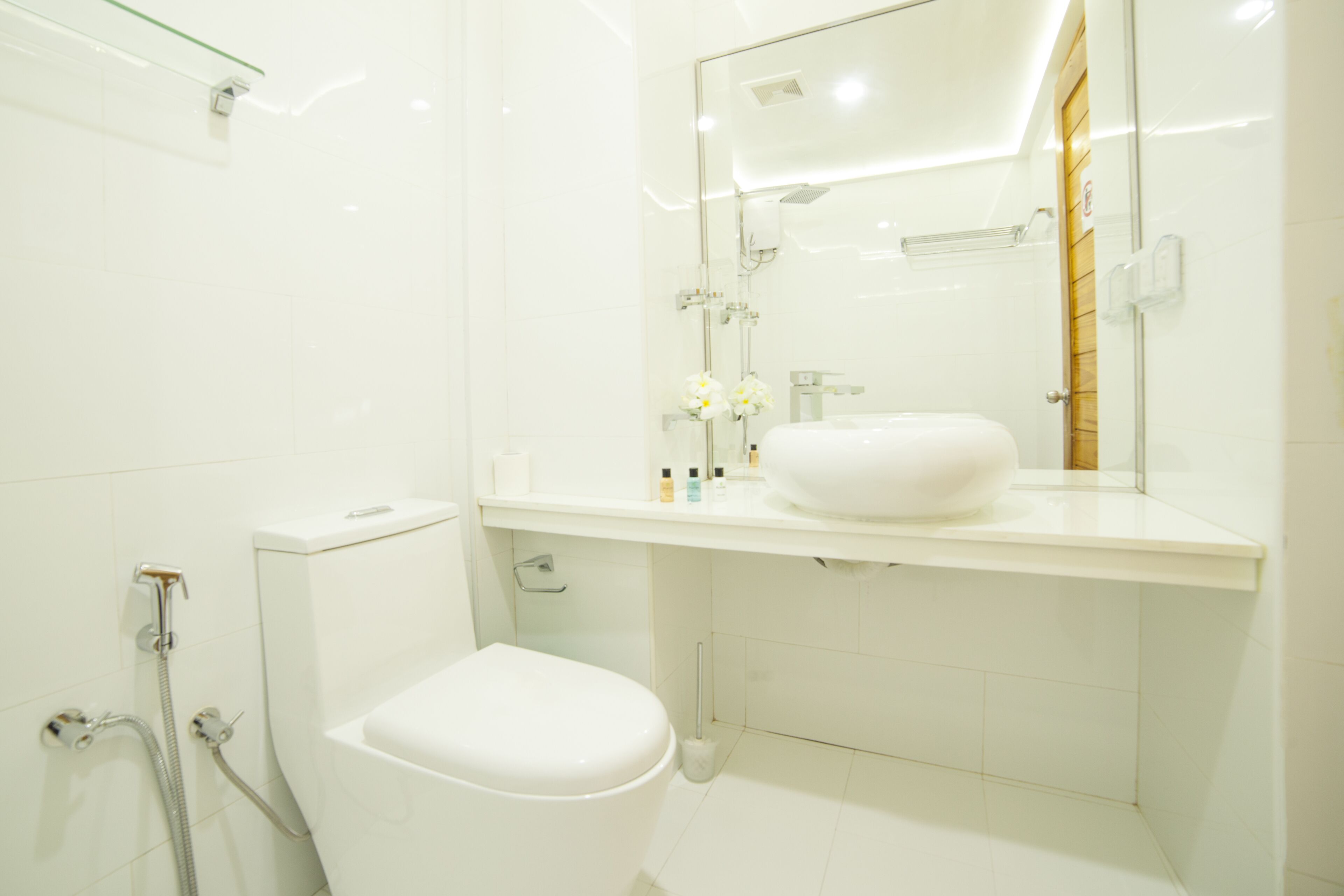 A modern bathroom with a white toilet, a glass shower enclosure, and a vanity with a white sink and mirror.