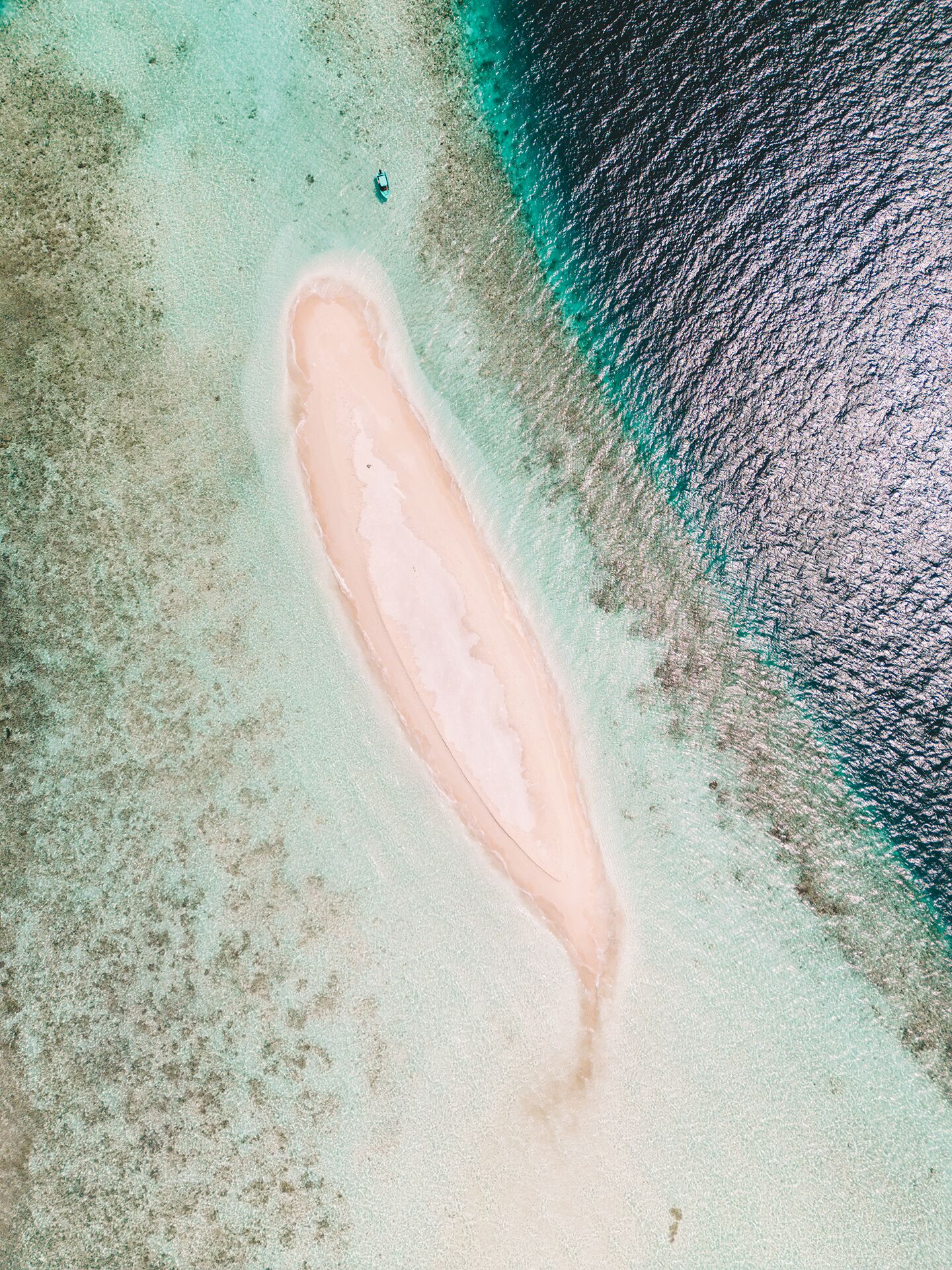 An aerial view of a beach with clear turquoise waters and a sandy shoreline.