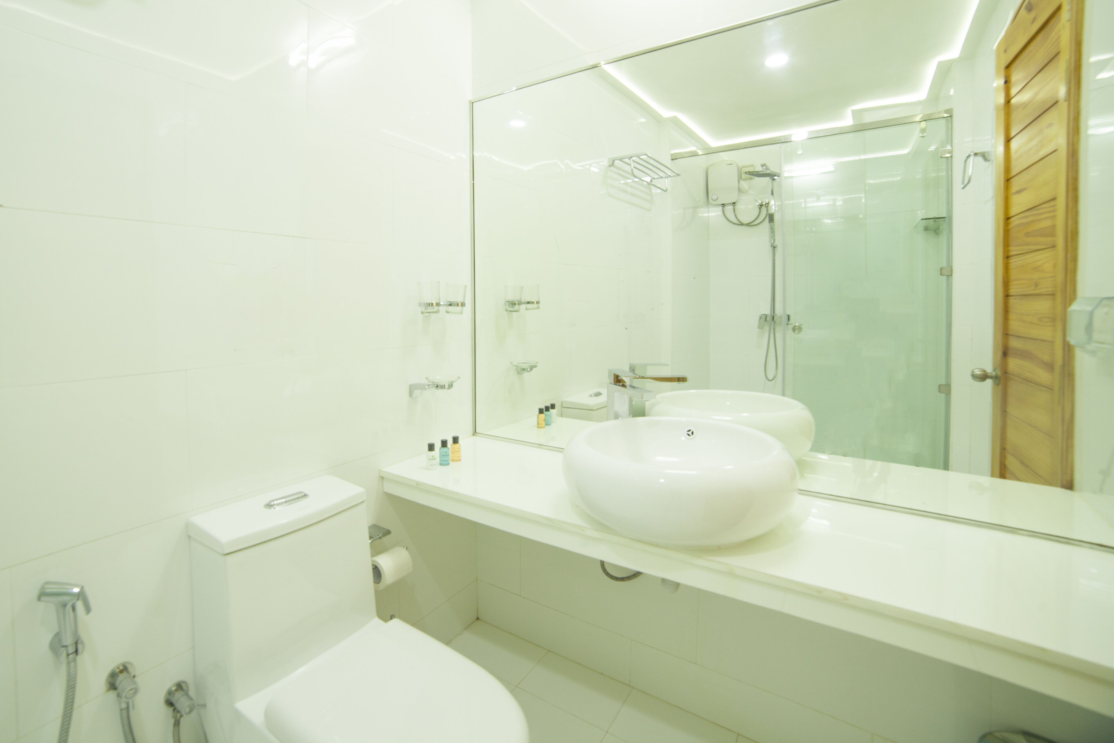 Un baño moderno con un espejo grande, dos lavamanos, una ducha y un inodoro.