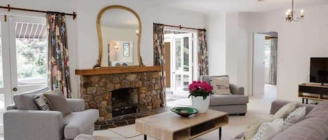A living room with a stone fireplace, grey sofas, a coffee table, and a television.