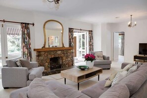 A living room with a stone fireplace, grey sofas, a coffee table, and a television.