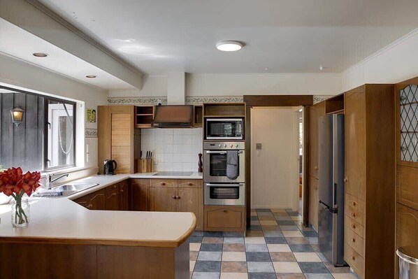 A kitchen with wooden cabinets, a central island, a built-in oven, and a refrigerator.