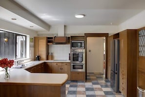 Eine Küche mit Holzausstattung, einer Kochinsel in der Mitte, einem eingebauten Backofen und einem Kühlschrank.