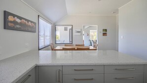 A modern kitchen with granite countertops, a dining area with a table and chairs, and a hallway leading to a living space.