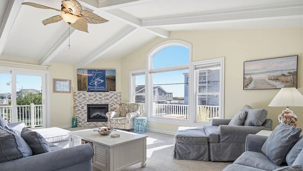 A spacious living room with a fireplace, large windows, and a balcony.