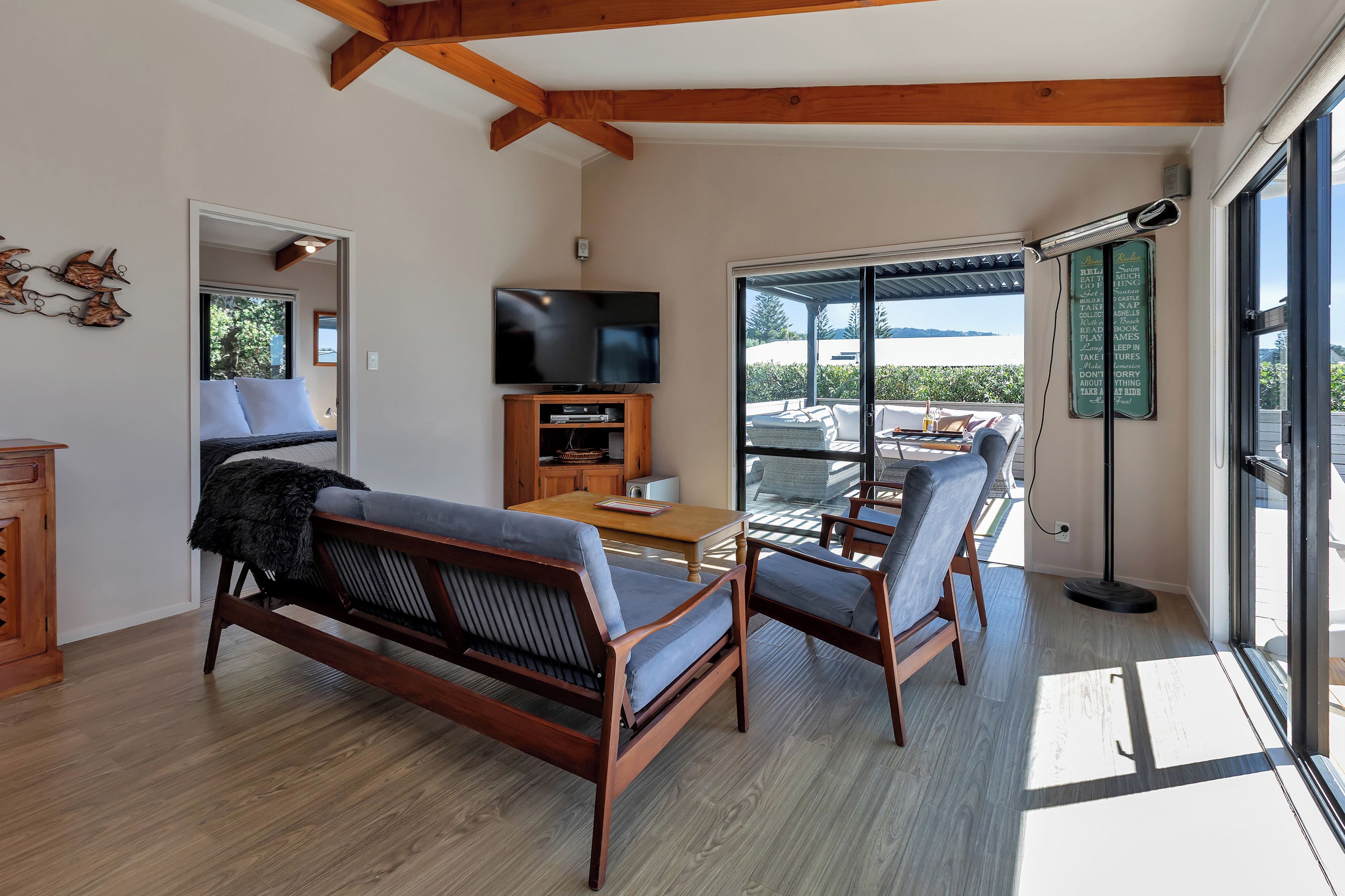 A modern living room with a sofa, chairs, a flat-screen TV, and a dining table.