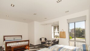 A bedroom with a bed, a chair, a small table, and a window. - The Ridge at Tairua - Tairua Apartment (Tairua)