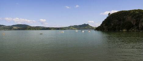 A calm lake with several boats anchored, surrounded by hills and a clear sky.
