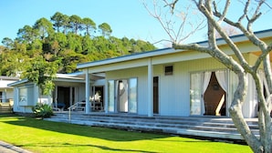 A single-story house with a covered porch, a small front yard, and a tree in front. - Paradise in Flaxmill Bay - Flaxmill Bay Home (Cooks Beach)