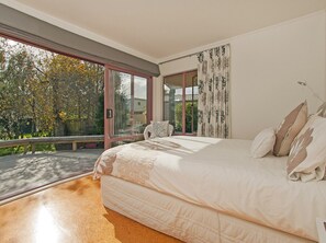 Ein Schlafzimmer mit einem großen Bett, Balkonblick und einem mit Vorhängen drapierten Fenster.