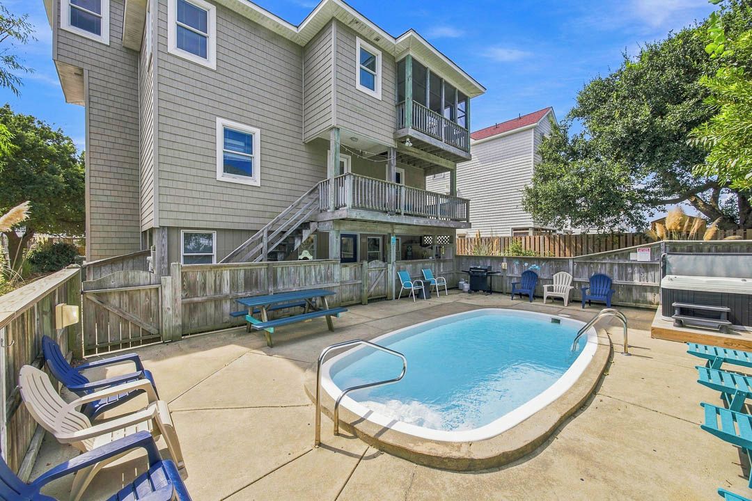 A two-story building with a swimming pool, outdoor seating, and a barbecue area.