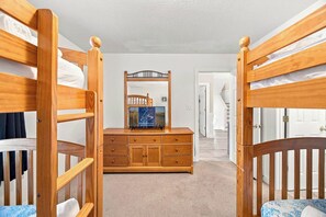 A bedroom with bunk beds, a dresser, and a mirror.